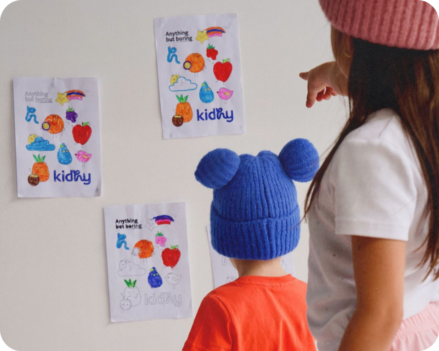 2 kids looking at kidhy colouring in sheets pinned to a white wall, hydration for kids