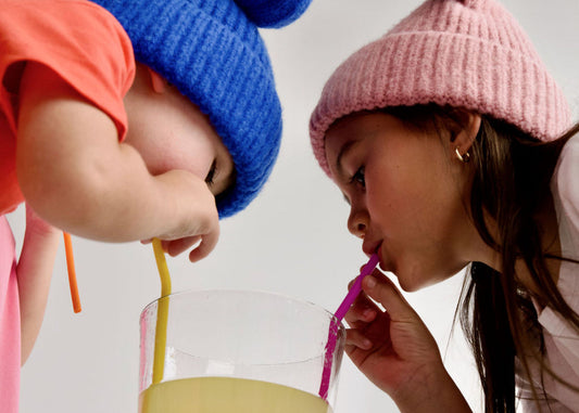 2 kids wearing kidhy beanies drinking kidhy hydration drink for kids through straws