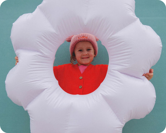 cute girl in pink kidhy beanie holding a white inflatable in the shape of a flower, kidhy hydration drinks for kids