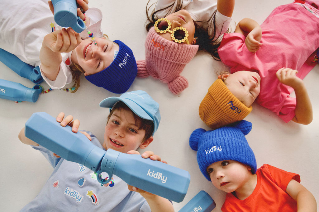 group of kids lying on the ground with kidhy beanies and kidhy drink bottles